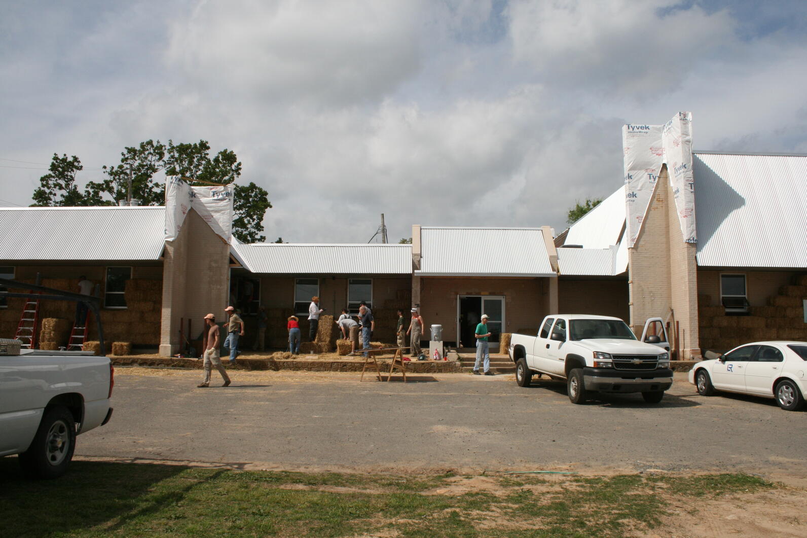 A building under construction with Tyvek paper still exposed. A group of people are at work in front of the building.