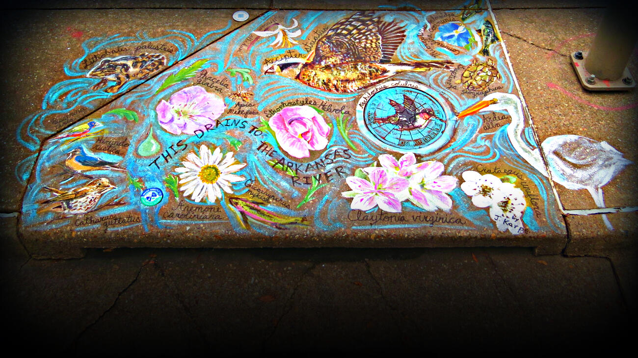 Painted artwork on a sidewalk with the words, this drains to the Arkansas River.